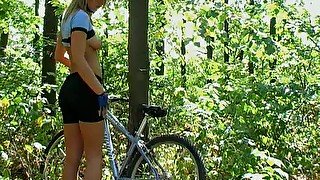 Booty blonde is posing near her bike deep in the forest