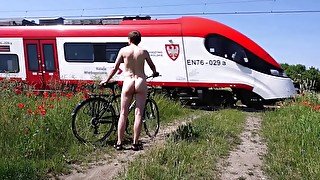 Naked with a bicycle at a railroad crossing, flashes at the passengers on the train