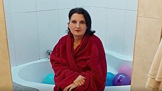 Mature brunette in the bathtub full of balloons