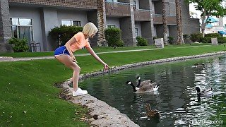 Outdoors video of solo blondie Kiara feeding the ducks in the pond