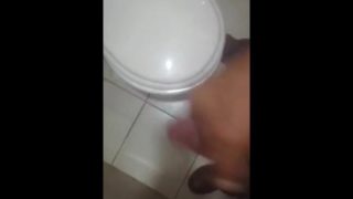 Hombre blanco tocandose en el baño del trabajo