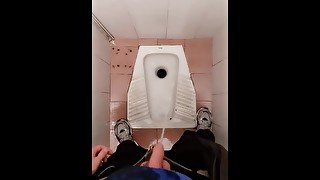 Young guy pissing in the public toilet