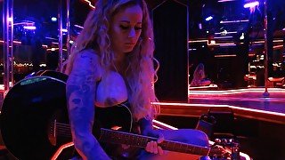 Playing guitar and singing a cover topless in club