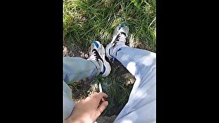 Young guy in sneakers and blue jeans smoke in the forest