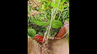 Village woman in a red tunic is pissing in the middle of a green field