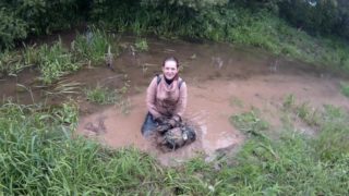 girl has fun in the mud in a blue dress