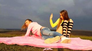 Two horny young lesbians masturbate together in the outdoors