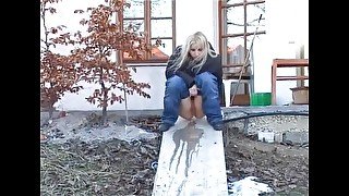 Slut pisses next to a house