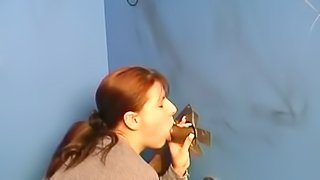 Redhead sucks a big cock out of a glory hole