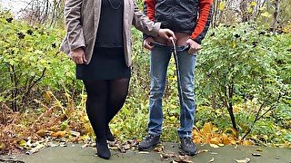 Hot milf in pantyhose and skirt holding guy's cock outdoors while pissing