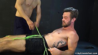 Muscular man tied up and blindfolded to be tickled by his friends