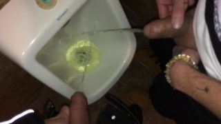 Boys piss and spit together at the urinal after some cocktails