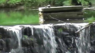 Sexy babe pees near a waterfall