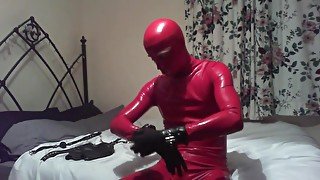 Self-hogtie in red latex rubber catsuit