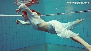 Elegant redhead goes swimming in her sexy clothes