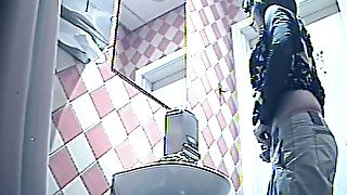 Brunette white lady in the public toilet room filmed from behind