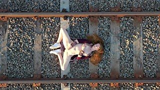 Horny redhead masturbates in public on country train tracks.