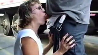 Mature woman sucks cock between trucks in parking lot