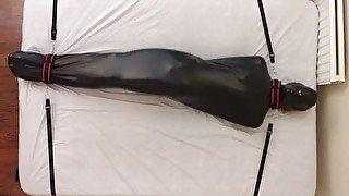 Sub in bondage bag tied down to the bed breathplay