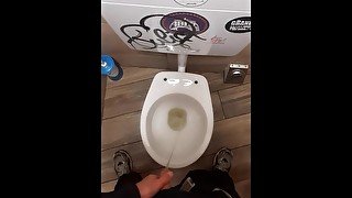 Young man pissing in a bar toilette