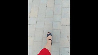 A girl in high heels walks around the city without panties