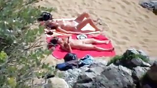 Two nude girls sun bathing on beach.