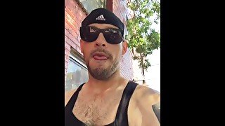 Muscular jock smokes while walking down downtown street