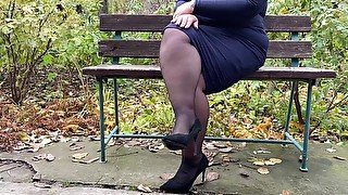 Lustful MILF in a long skirt and stockings masturbates on a park bench