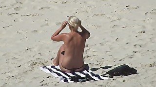 Topless blonde MILF in sunglasses flashed her nice bum on the beach