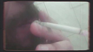 Bearded man smoking and shaving his pubic hair