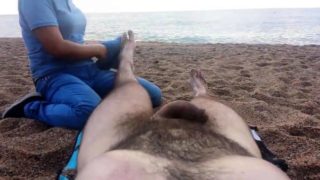 Lucky guy has a sexy lady massaging his feet on the beach