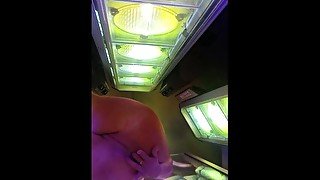 Heat from the tanning bed makes her hot and wetwet