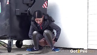 Shiny leggings girl pees behind a dumpster