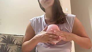 Woman plays with small pink balloon (the balloon doesn't burst)