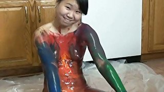 Playful Asian chick is painting on her naked body in the kitchen