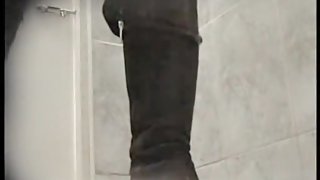 Amateur in high boots sits pissing in public toilet