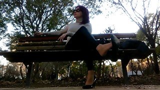 I am dangling my black pumps and my leather pants on a bench in the park