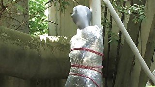 Bondaged and cocooned slave girl in the mystery garden - Full encasement fetish in zentai body bag