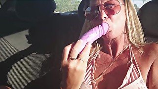 Fucking a dildo in the backseat of a car parked on a busy road. Giving a little masturbation encouragement.