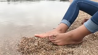 Ebony teen feet at the shore gets covered in sand.