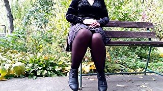 Peeing with legs spread wide on a bench in an autumn park