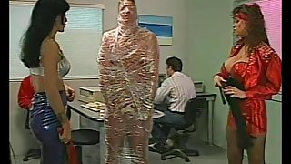 Mistresses cover a man in tight plastic wrap