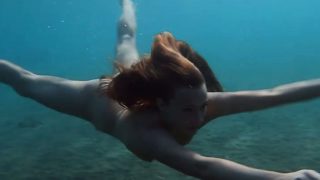 Julia is swimming underwater nude in the sea