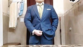 Сheerful business man fingering in a suit in front of a mirror