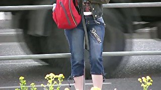 Brunette girl in the city urinates right in her jeans